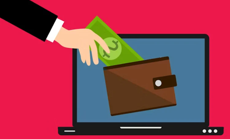 Hand inserting a green dollar bill into a digital e-wallet displayed on a laptop screen against a pink background